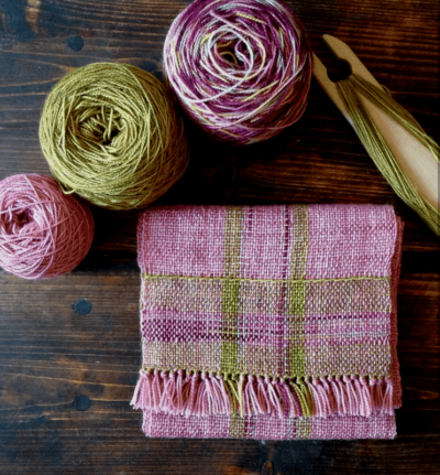 A pink and green handwoven scarf using a rigid heddle loom