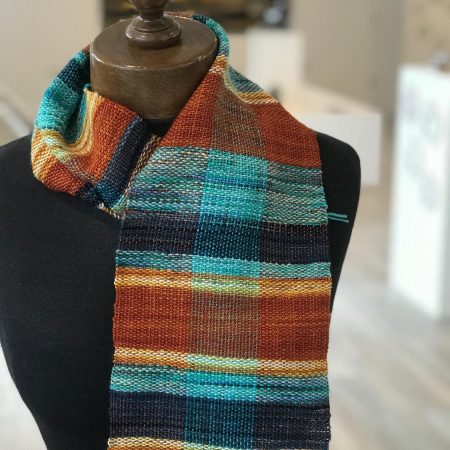 A scarf woven by a complete beginner using a rigid heddle loom. Using blue, orange and yellow yarn