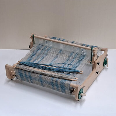 Flex Rigid heddle loom, on a table warped up in shades of blue yarn